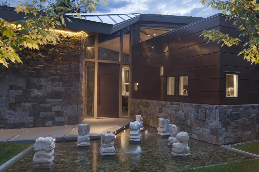 A unique luxury home at night and its backyard pond