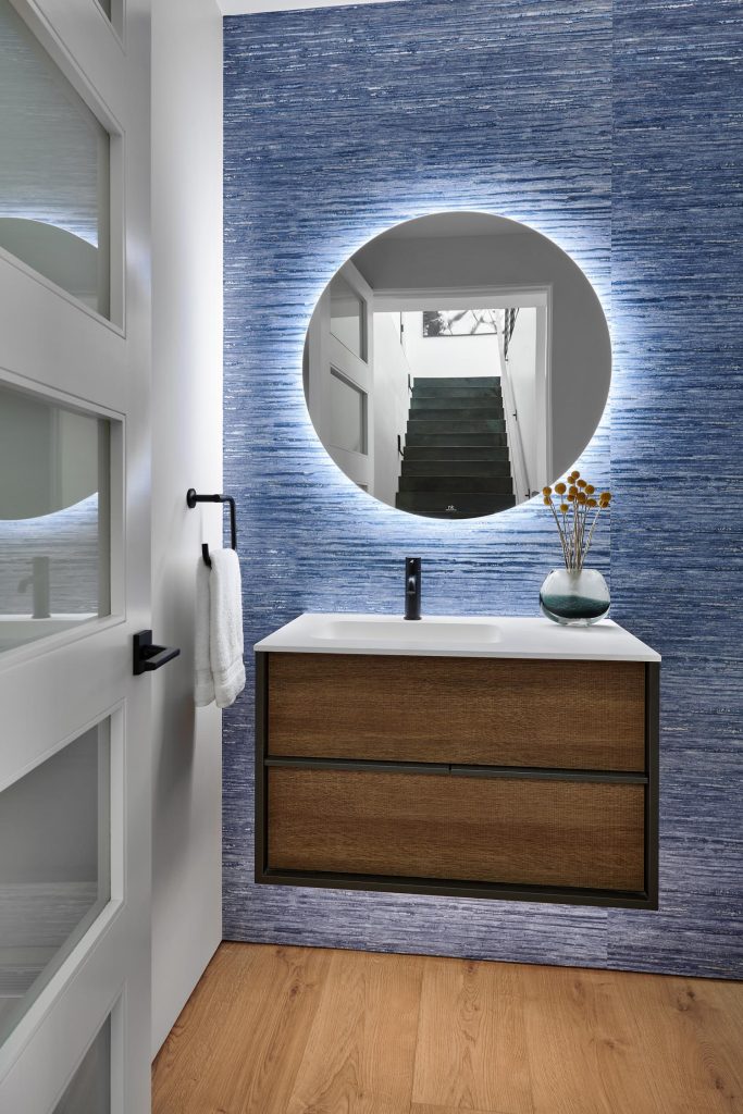 A backlight circular mirror against an accent wall in a luxury bathroom