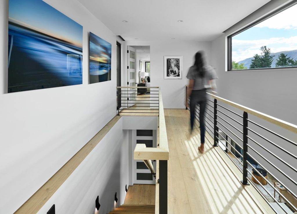 A staircase with an elevated, unenclosed hallway that lets in light