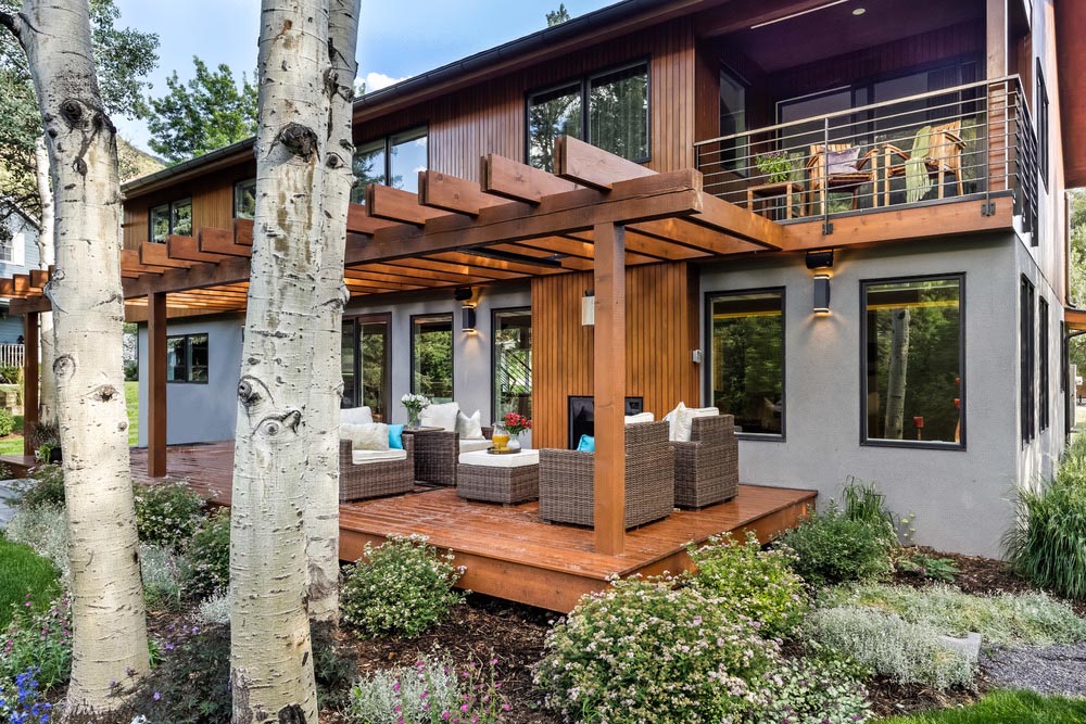 The back porch of a home with outdoor seating options, and a view of the upper balcony