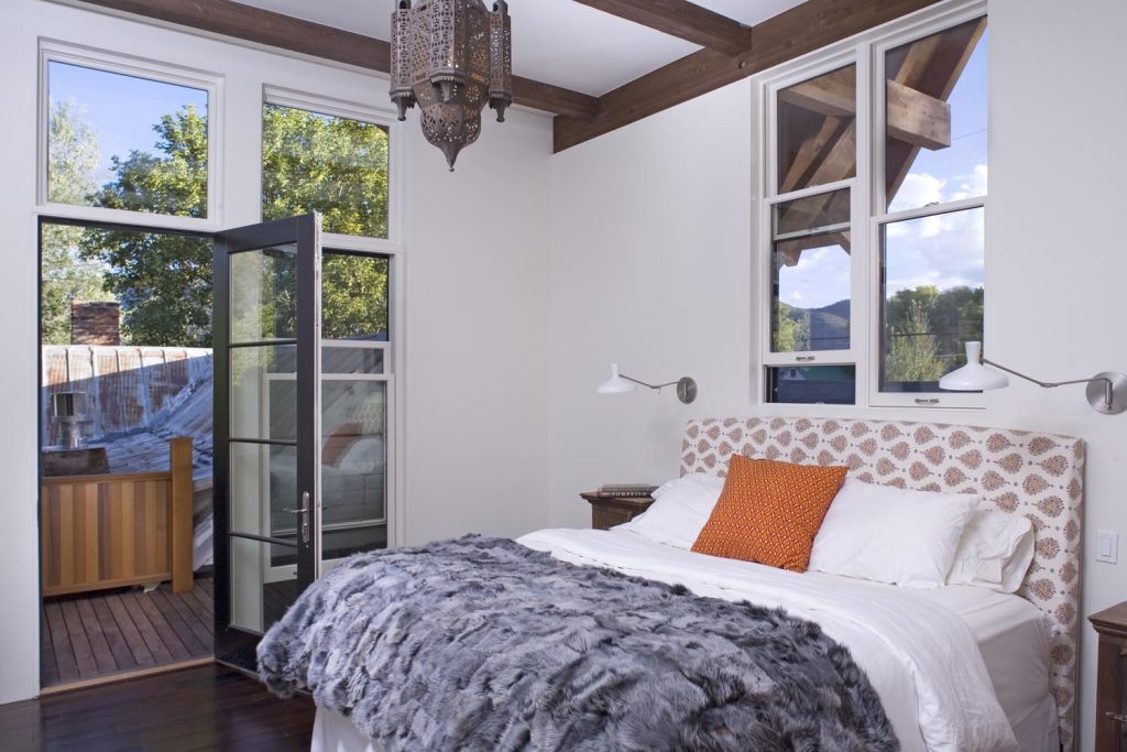 A luxury bedroom with a chandelier and an outdoor balcony