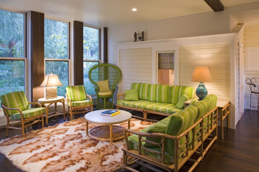 An enclosed sunroom with green furniture