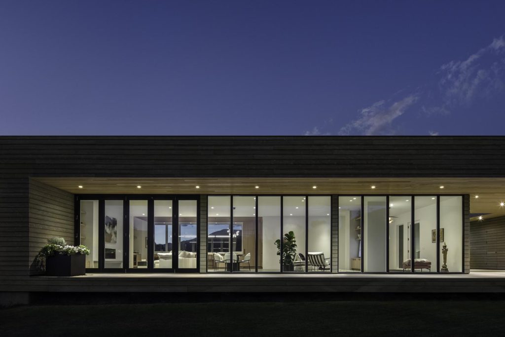 A night view of a home with large glass windows