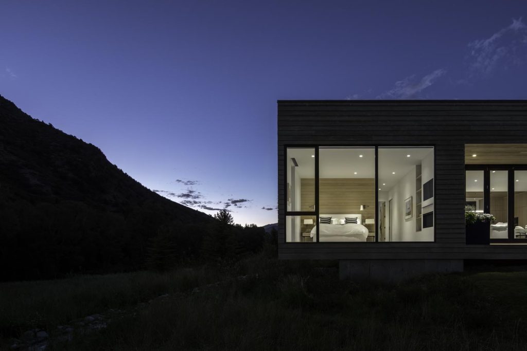 A night view of a home with large glass windows