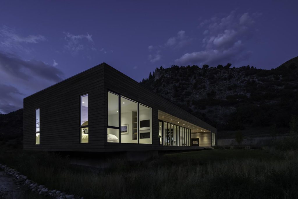 A night view of a home with large glass windows