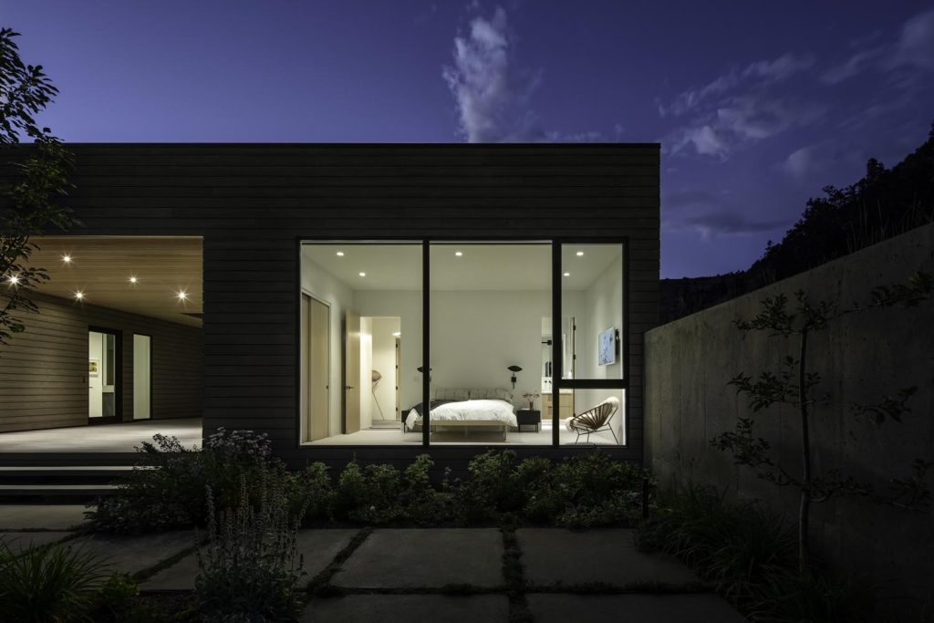 A night view of a bedroom with large glass windows