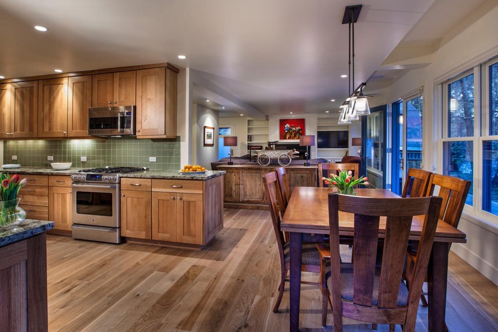 This warm wooden kitchen has green backsplash and an open floor plan leading to the living room