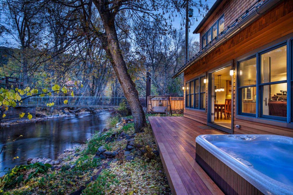 A back porch with a jacuzzi, looking out onto a river and bridge