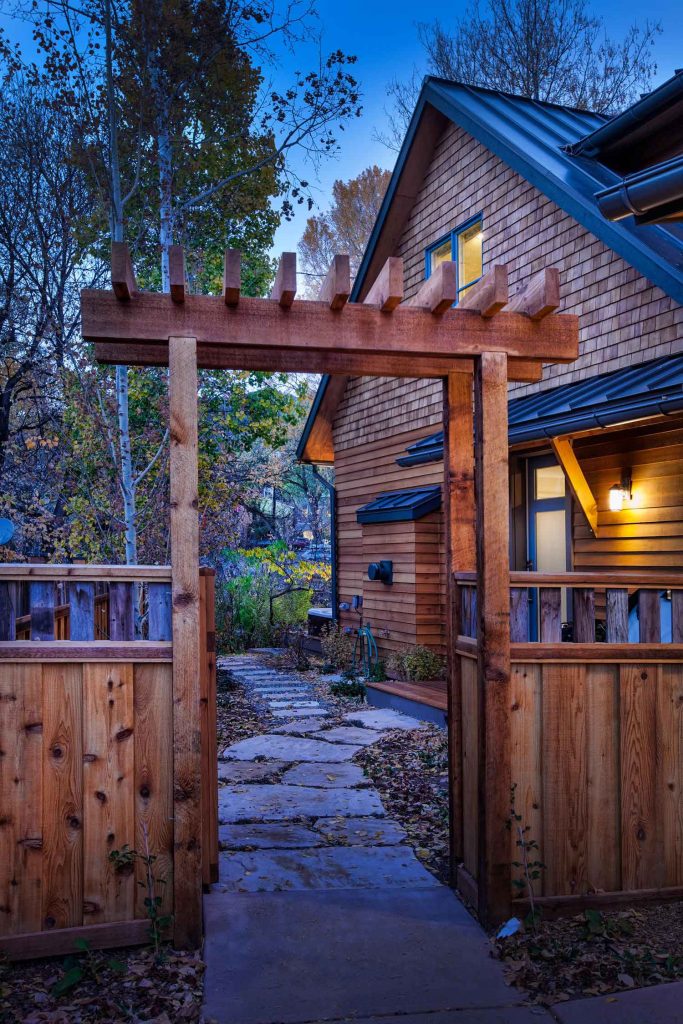 A view of a custom home and its backyard entryway, fenced with warm wood