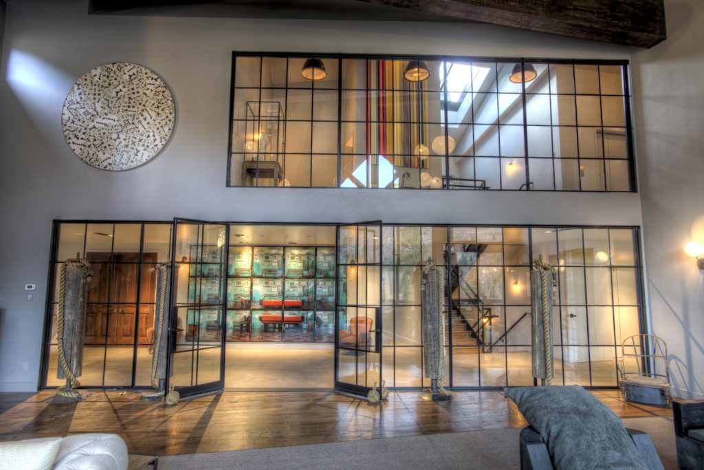 A two-story wall looking into a living room, made almost entirely of geometric glass