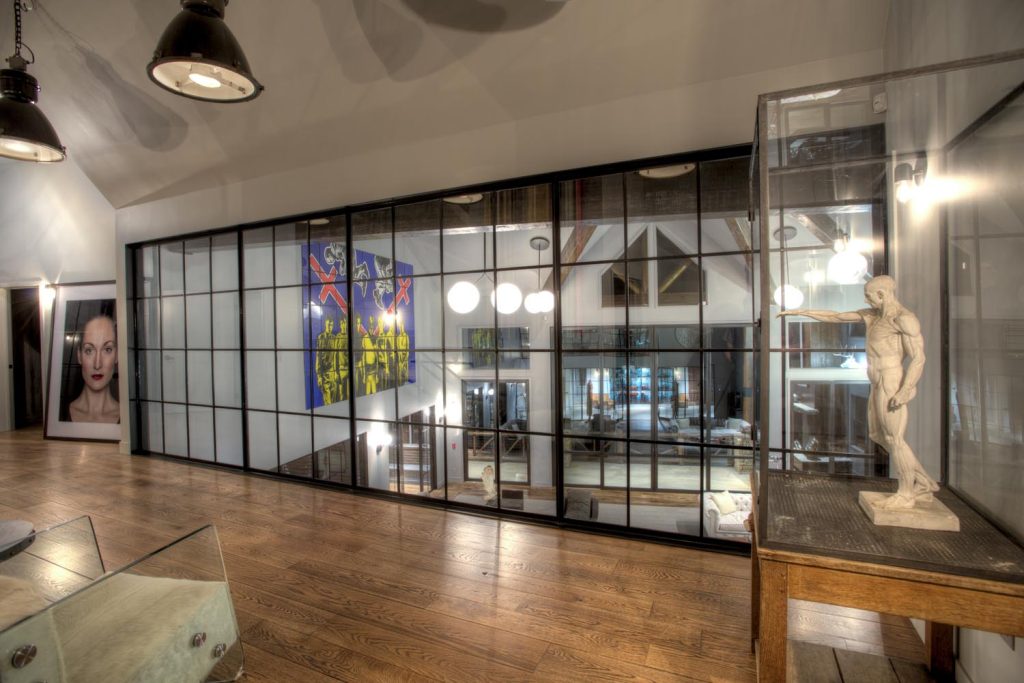 An art statue of a man pointing towards glass windows overlooking a living room