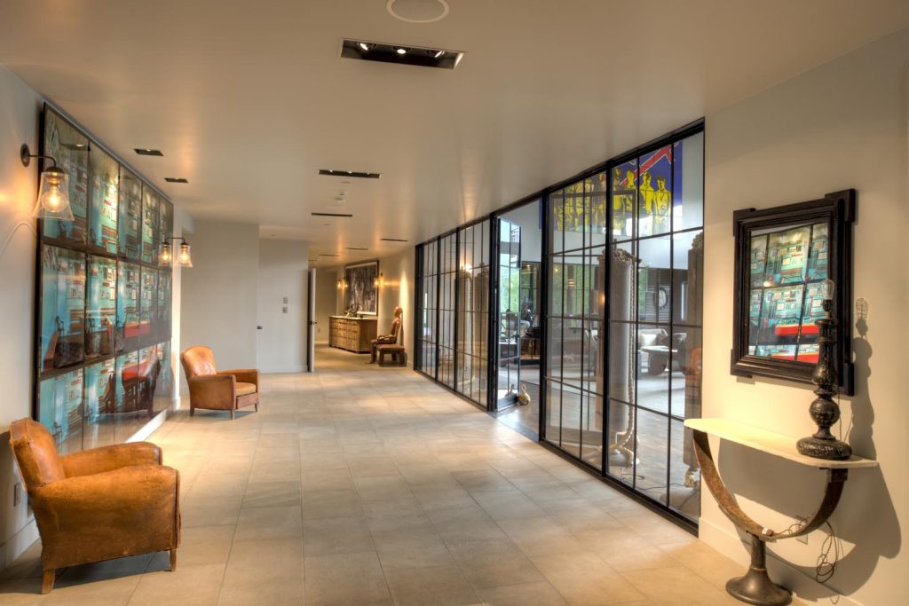 Glass paneling makes up the wall of this lounge area that leads to the living room of a luxury home